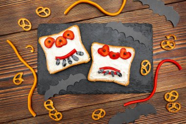 Cadılar bayramında kızarmış ekmek, tereyağı, çilek, şeker, servis tahtası, siyah arka planda yarasalar. Çocuklar tatlı tatlı tatlı kahvaltı öğle yemeği.