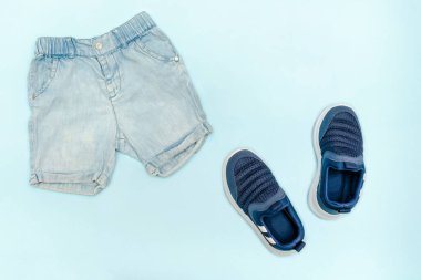 Yaz bebekleri mavi kıyafetler ve kot şortlu aksesuarlar, spor ayakkabılar. Modern moda çocuk kıyafetleri. Bahar ya da yaz için çocuk kıyafetleri. Düz konum, üst görünüm, genel görünüm, kopyalama alanı ile modelleme.