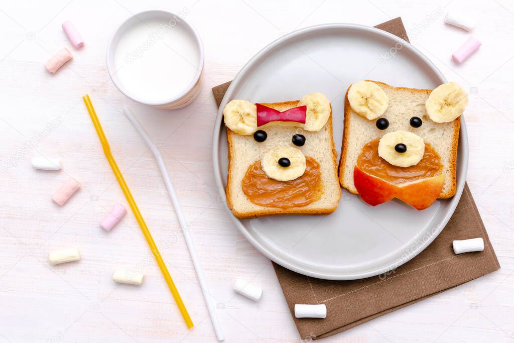 Funny cute bear,dog faces sandwich toast bread with peanut butter, banana, apple,milk, marshmallow. Kids childrens baby's sweet dessert healthy breakfast lunch food art on plate,close up,top view.
