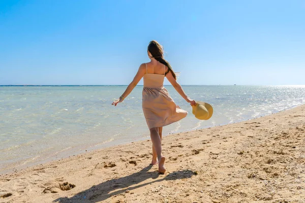 Young adult female woman person with hat enjoy relaxing on sea,walk along ocean beach,coast in luxury resort,looking on blue clear water.Summer travel tropical recreational vacation tourism concept.