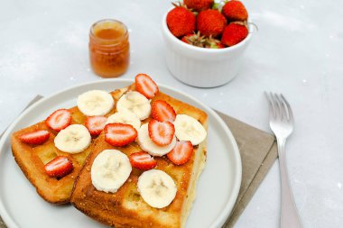Çilekli Belçika waffle 'ı, muz, konsantre süt, tabakta bal. Lezzetli kahvaltı, tatlı tatlı yiyecekler. Seçici odak, üst manzara düzlüğü..