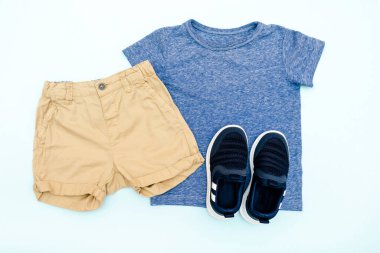 Yaz bebekleri mavi elbiseler ve tişörtlü aksesuarlar, şort, spor ayakkabılar. Modern moda çocukları gündelik kıyafetler. İlkbahar için çocuk kıyafetleri. Düz yatış, üst görünüm, genel görünüş, model.
