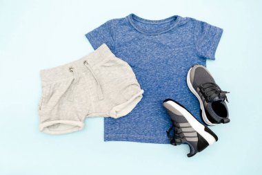 Yaz bebekleri mavi elbiseler ve tişörtlü aksesuarlar, şort, spor ayakkabılar. Modern moda çocukları gündelik kıyafetler. İlkbahar için çocuk kıyafetleri. Düz yatış, üst görünüm, genel görünüş, model.