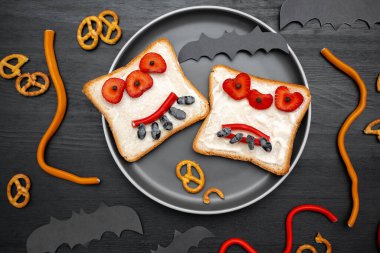 Cadılar bayramında kızarmış ekmek, tereyağı, çilek, şeker, servis tahtası, siyah arka planda yarasalar. Çocuklar tatlı tatlı tatlı kahvaltı öğle yemeği.