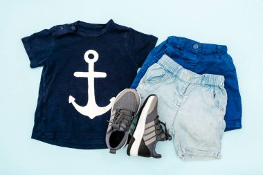 Yaz bebekleri mavi elbiseler ve tişörtlü aksesuarlar, şort, spor ayakkabılar. Modern moda çocuk kıyafetleri. Bahar ya da yaz için çocuk kıyafetleri. Düz yatış, üst görünüm, genel görünüş, model.