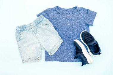 Yaz bebekleri mavi elbiseler ve tişörtlü aksesuarlar, şort, spor ayakkabılar. Modern moda çocukları gündelik kıyafetler. İlkbahar için çocuk kıyafetleri. Düz yatış, üst görünüm, genel görünüş, model.