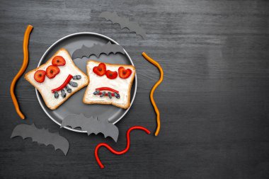 Cadılar bayramında kızarmış ekmek, tereyağı, çilek, şeker, servis tahtası, siyah arka planda yarasalar. Çocuklar tatlı tatlı tatlı kahvaltı öğle yemeği.