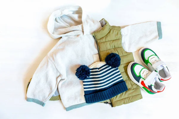 Vest,jumper,sweater and hat with sneakers. Set of baby children\'s clothes,clothing and accessories for spring, autumn or winter on white background. Fashion kids outfit. Flat lay, top view, overhead