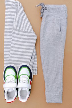 Bebek ayakkabısı, tişört, kazak ve kot pantolon. Bahar, sonbahar ya da yaz için çocuk kıyafetleri ve aksesuarlar. Moda çocuk kıyafetleri, bej rengi kahverengi arka plan..