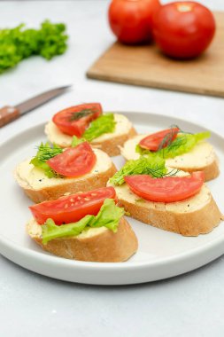 Yumuşak beyaz peynirli ricotta, taze domates, ahşap kesim tahtasında fesleğen yeşili. Lezzetli sağlıklı vejetaryen yemeği, İtalyan aperatifi. Üst görünüm düzlüğü.