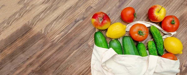 Detox diet fitness vegetarian vegan healthy food for dinner,proper nutrition with fresh fruits and vegetables in eco bag on wooden background top view copy space flatly flat lay.Set of autumn harvest.