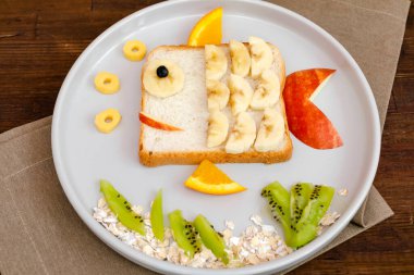 Muzlu, elmalı ve portakallı sandviç ekmeği. Çocukların tatlıları sağlıklı kahvaltı tabakları, ahşap arka plan, üst manzara..