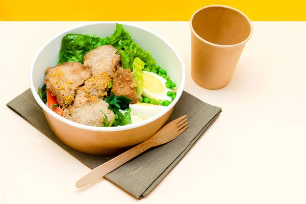 Healthy food lunch in kraft paper carton eco friendly box disposable bowl packaging container, cup on yellow background. chicken, eggs, greens. Take away delivery. environment protection top view.