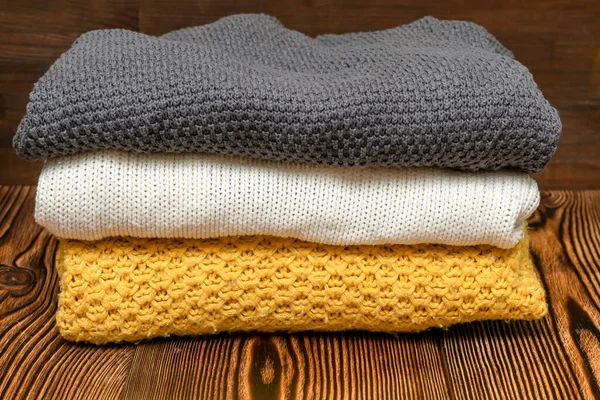 Home wardrobe with winter clothes. Stack of folded cashmere warm woolen knitted sweaters casual womens clothes. Autumn, winter cold season knitwear.
