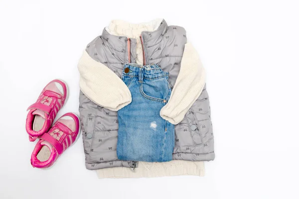 Vest,warm jumper,sweater,jeans pants,pink sneakers.Set of baby children's clothes,clothing for spring,autumn,winter on white background. Fashion girls kids outfit.Flat lay,top view, overhead,mockup.