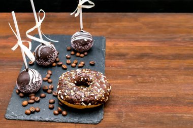 Çikolatalı kek, tahta tahtaya beyaz serpiştirilmiş donut kahve çekirdekleri ahşap arka planda, lezzetli pastalar, çubukta tatlılar. Lezzetli yemek düzleştirir, serer.