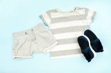 Yazlık bebekler gri kıyafetler, tişört, şort, spor ayakkabı. Modern moda çocukları gündelik kıyafetler. İlkbahar için çocuk kıyafetleri. Düz yatış, üst görünüm, genel görünüş, model