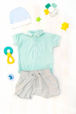 Şirin bebek tulumu, mayo, şort, şapka, oyuncak çoraplar, pantolon askısı. Çocuklar, çocuk kıyafetleri ve pastel mavisi aksesuarlar. Yeni doğan, bebek modası, kıyafet. Düz yatış, üst görünüm.