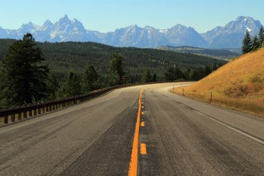 ABD 'nin Wyoming eyaletindeki Grand Teton Ulusal Parkı' nın muazzam dağlarına doğru giden manzaralı bir otoyol var.