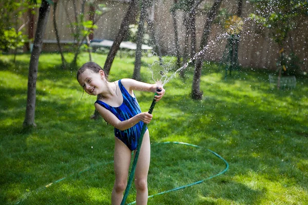 Fata pulverizează apă dintr-un furtun Imagine de stoc