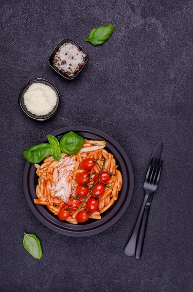 Pasta with tomatoes, red sauce and cheese on a black background. Selective focus. Top view.