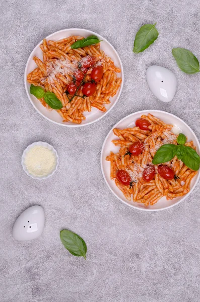 Pasta with tomatoes, red sauce and cheese on a gray background. Selective focus. Top view.