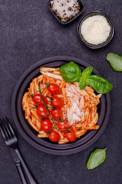 Pasta with tomatoes, red sauce and cheese on a black background. Selective focus. Top view.