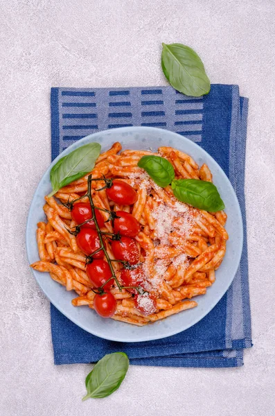 Pasta with tomatoes, red sauce and cheese on a gray background. Selective focus. Top view.