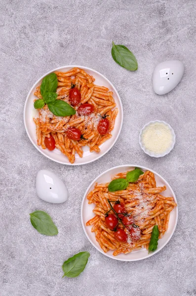 Pasta with tomatoes, red sauce and cheese on a gray background. Selective focus. Top view.