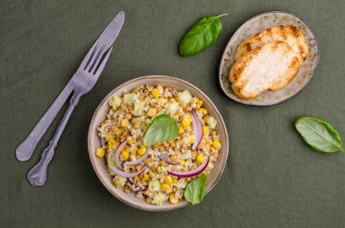 Buğday ve sebzeli mercimek salatası. Tekstil arka planında seramik bir kapta. Seçici odak. 