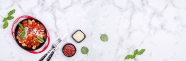 Domatesli gnocchi, kırmızı sos, mermer zemin üzerinde peynir ve fesleğen yaprakları. Seçici odaklanma. Üst görünüm. 