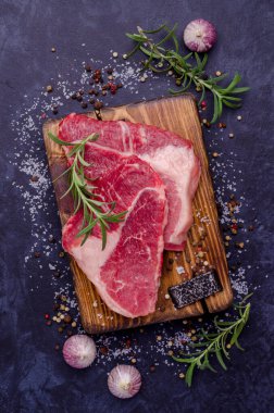 Baharatlı iki çiğ biftek. Geçmişi karanlık. Seçici odak. 