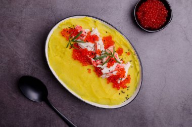 Sarı püre, yengeç eti ve kırmızı havyar. Taş zemin. Seçici odak.