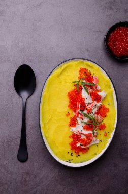 Sarı püre, yengeç eti ve kırmızı havyar. Taş zemin. Seçici odak.