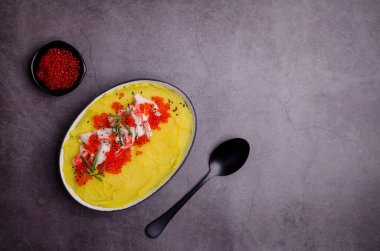 Sarı püre, yengeç eti ve kırmızı havyar. Taş zemin. Seçici odak.