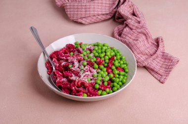 Seramik tabakta yeşil bezelye ve peynirli pancar makarnası. Seçici odak.