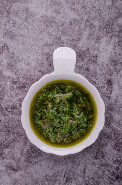 Seramik tabaklarda yeşil sos, gri taşlı arka planda. Seçici odaklanma. Üst görünüm.