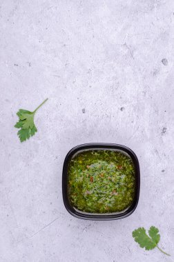 Seramik tabaklarda yeşil sos, gri taşlı arka planda. Seçici odaklanma. Üst görünüm.