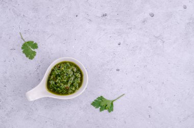 Seramik tabaklarda yeşil sos, gri taşlı arka planda. Seçici odaklanma. Üst görünüm.