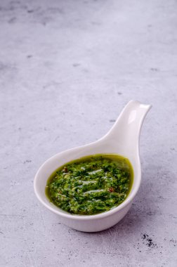 Seramik tabaklarda yeşil sos, gri taşlı arka planda. Seçici odak.