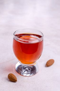 Açık arkaplandaki bardakta şeffaf kahverengi sıvı. Seçici odak.