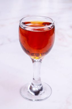 Açık arkaplandaki bardakta şeffaf kahverengi sıvı. Seçici odak.