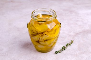 Hafif bir arka planda cam bir kavanozda kızarmış enginar dilimleri. Seçici odak.