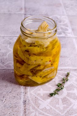 Hafif bir arka planda cam bir kavanozda kızarmış enginar dilimleri. Seçici odak.