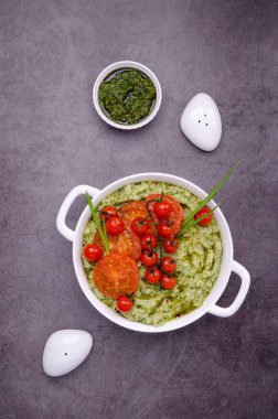 Baharatlı yeşil patates püresi ve koyu arkaplanda seramik bir tabakta kızarmış domates. Üst görünüm.