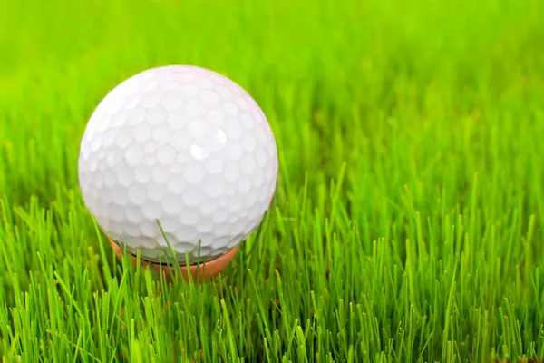 Golf ball on tee over a green. — Stock Photo, Image