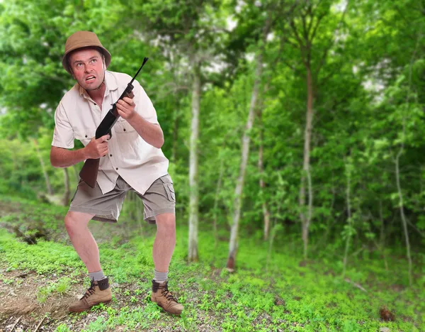 Забавная картина сумасшедшего охотника с охотничьей винтовкой в тропическом лесу — стоковое фото