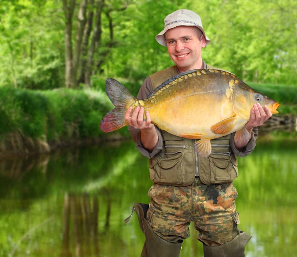 Fiskaren med hans stora karp på en vacker älv. — Stockfoto