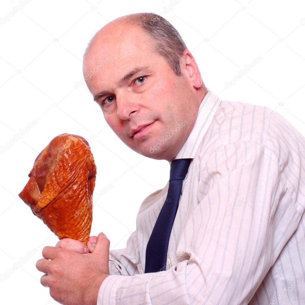 Hungry businessman eating ham.