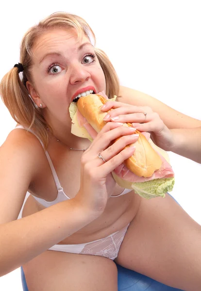 Mujer con sobrepeso sentada en una pelota de fitness comiendo sándwich grande . — Foto de Stock